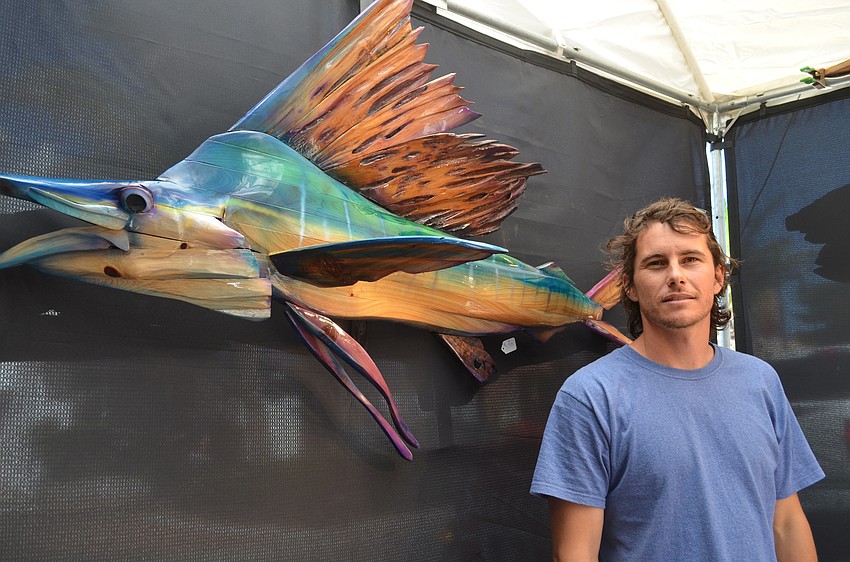 Dustin Cole with one of the wooden sculptures he has on display at Siesta Fiesta.