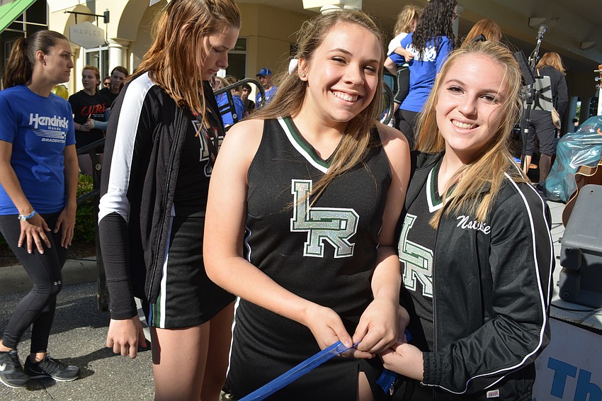 Lakewood Ranch High School cheerleaders Kara Mathis and Natalie Fonseca hold a ribbon to mark the race's starting line.