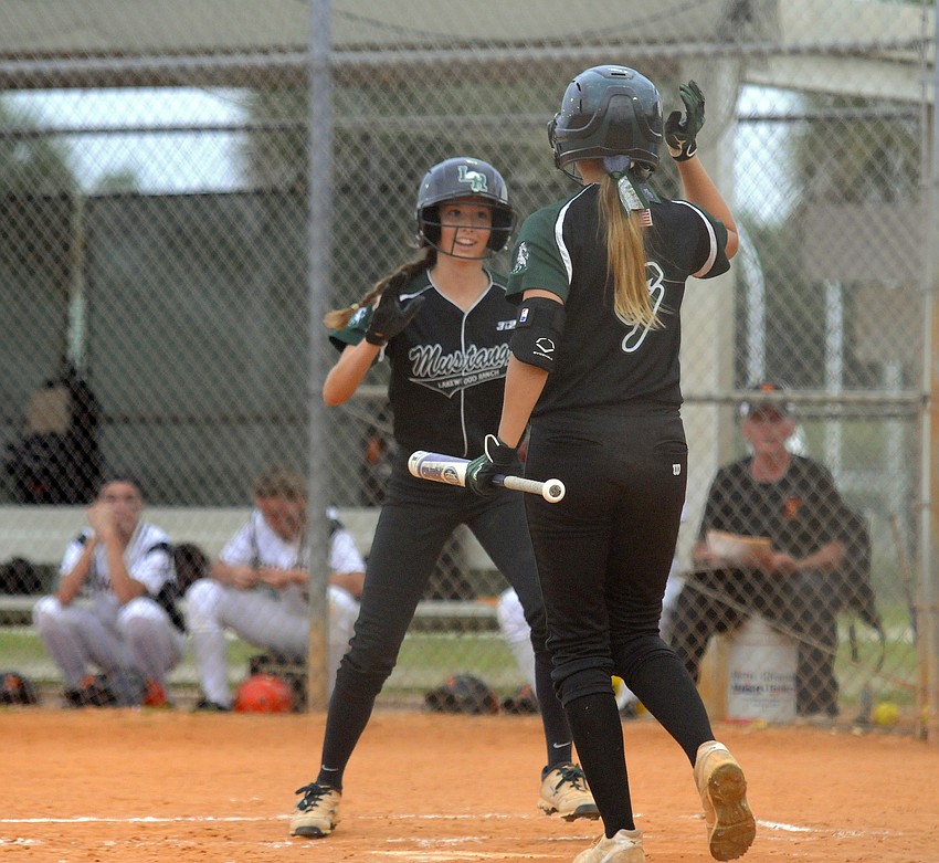 Lakewood Ranch leadoff hitter Denali Schappacher is congratulated by Mackenzie Meyer after scoring the Mustangs first run of the game.