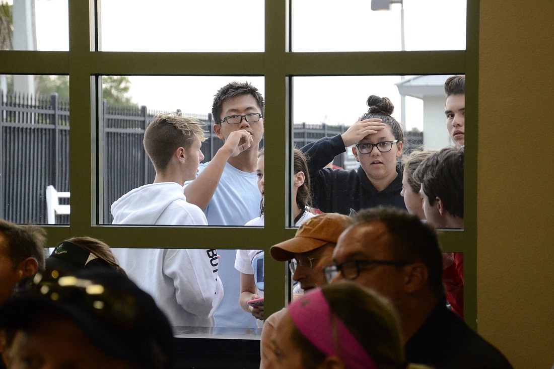 Jacob Myer, Mason Zhang and Isabella Ortiz, all Blackfins swim team members, anxiously watch the parent-YMCA staff meeting from outside. Manatee County YMCA CEO asked all the under-18 members to leave  for the heated debate over the team's dissolution.