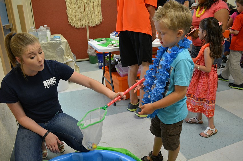 Braden River High School's Camryn Diss helps Kaleb Nonnemaker, 4, 