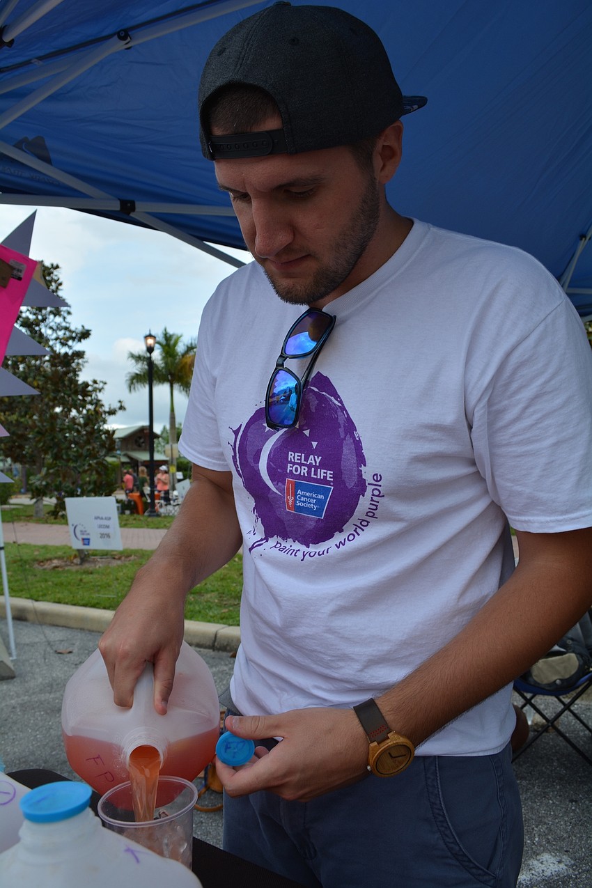 Derek Standke, of Sarasota, serves a multivitamin drink to raise money for Team CO to WISCO.