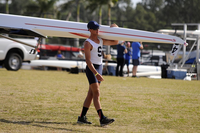 Sarasota Crew's Trey Whitten carries his boat down to the water for the Boys Junior 2x final.