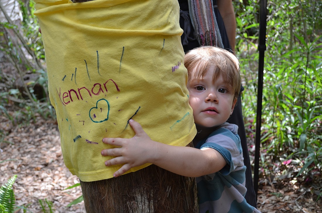 Kennan Wilson hugs a tree that he helped decorate with his mother Gina at the Hug-a-tree event last year at the Sarasota Children's Garden.