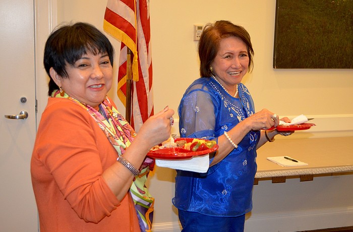Vicky Imperial and Maria Cora Gaffar, president of the Asian Women's Club of Lakewood Ranch, snack on Filipino cuisine.
