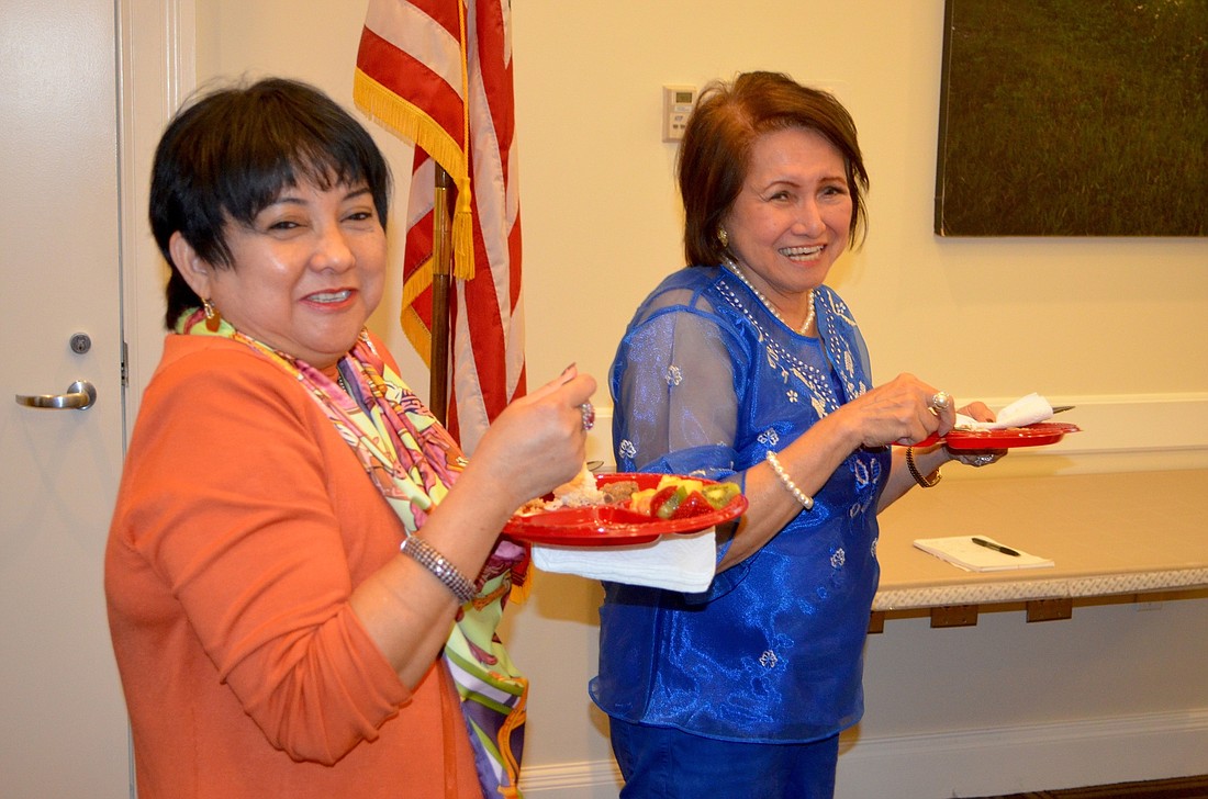 Vicky Imperial and Maria Cora Gaffar, president of the Asian Women's Club of Lakewood Ranch, snack on Filipino cuisine.