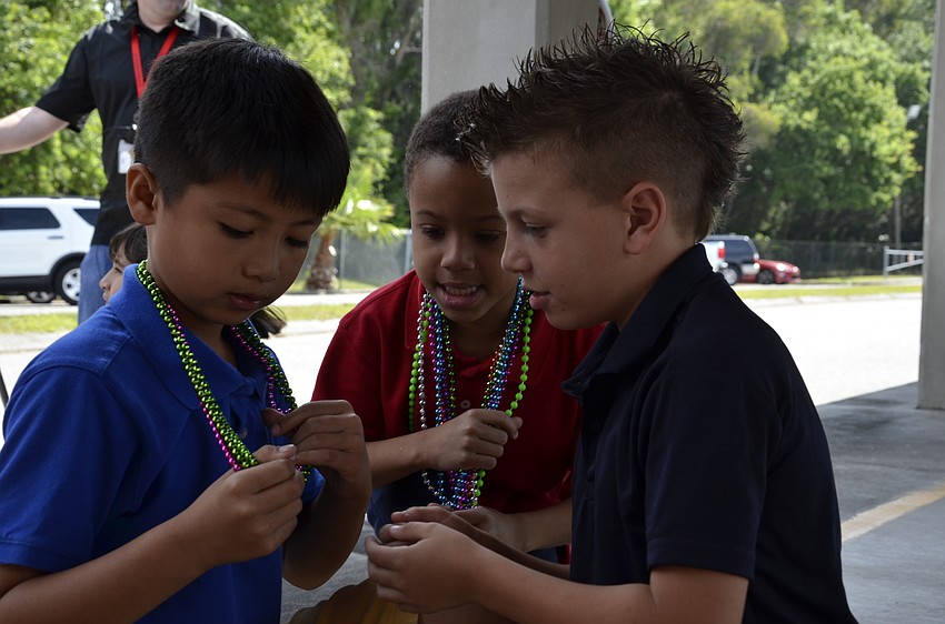 Third-graders Jason Pha, Caden Ogilvie and Ryan Peawelkoski compare their necklaces.
