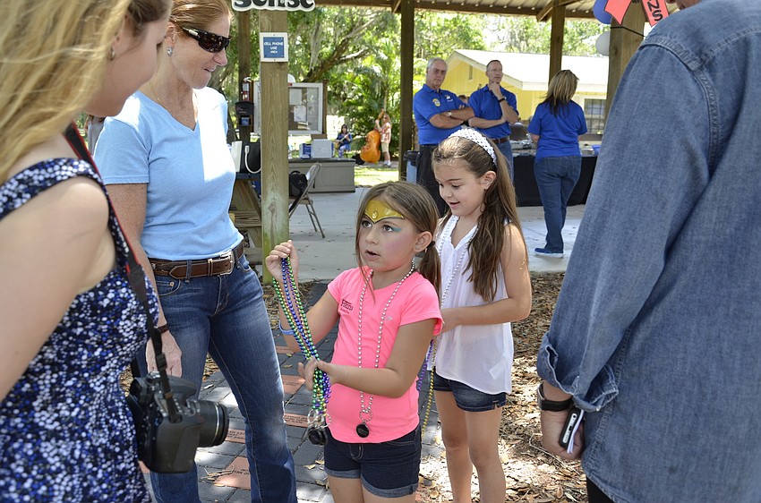 Abby Koch of Bradenton offers a necklace to mural artist Natalie Palumbo and event coordinator Jody Jorgensen.