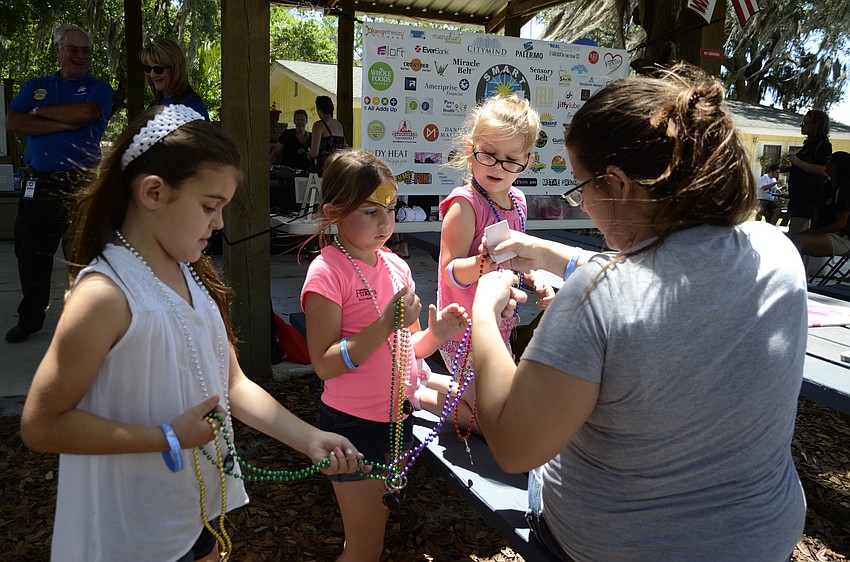 Isabella Thomas of Sarasota and Abby Thomas of Bradenton give necklaces to Englewood resident Melissa Harris and her daughter Kailey Evans.