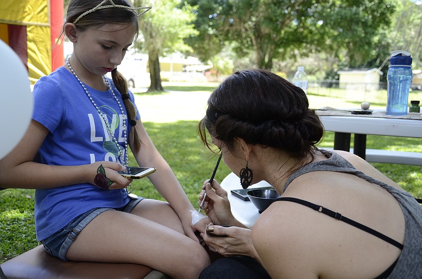 Madison Koch of Bradenton gets a horse painted on her hand by Sally Mamalis.