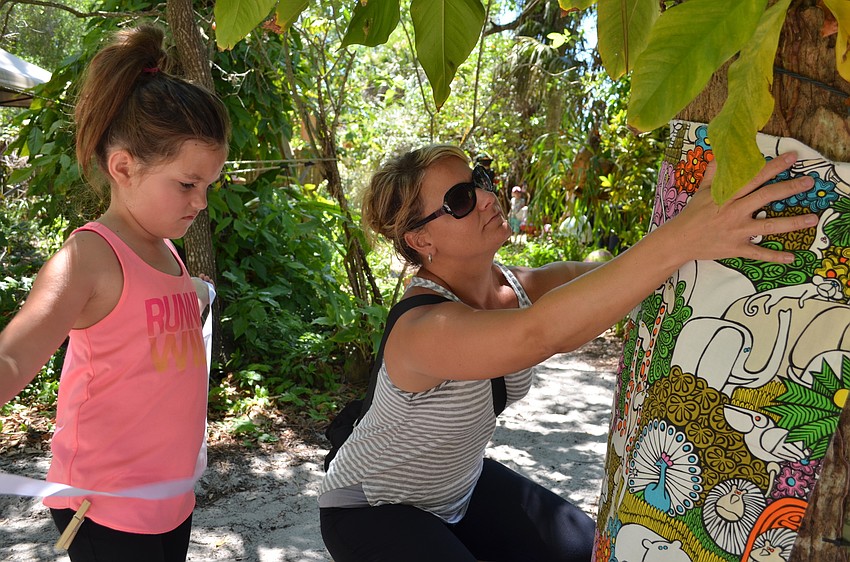 Savannah helps her mother Rechele Hoffman wrap a tree.