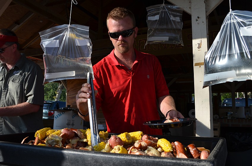 Parker Archibald serves up corn, sausage, crab legs and potatoes.