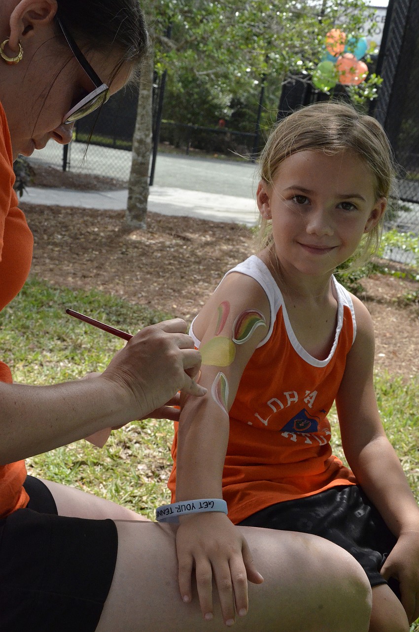 Addison Crutchfield of Lakewood Ranch gets her arm painted by volunteer Bridgette Gutierrez.