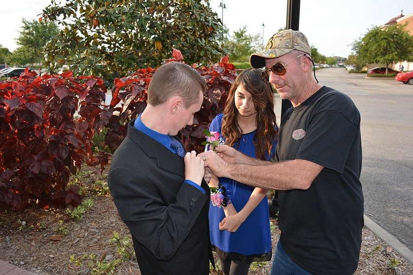 Crystal Erberfeld watches closely as her dad, Dale Kingsland, pins a boutonniere on her date, Stirling Lamb. Erberfeld is a sophomore and Lamb is a junior.