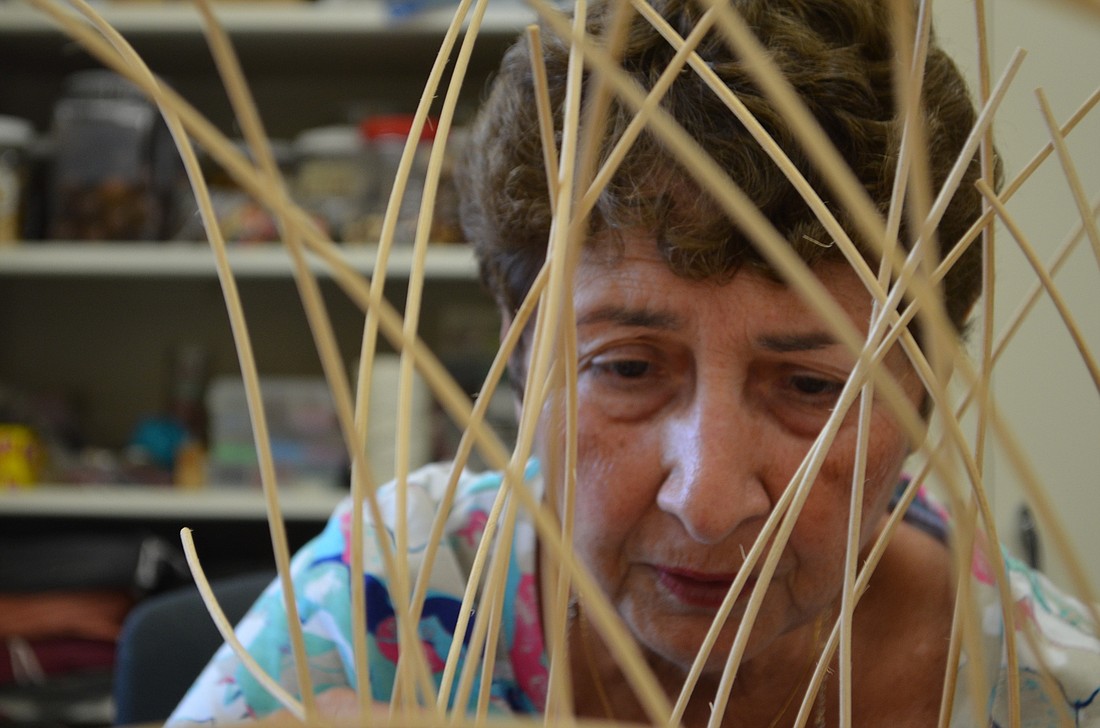 Frances Worman weaves reeds in a design for a basket for her daughter.