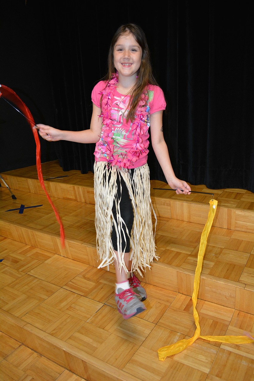 Jessica Dolan, 7, warms up for the musical performance, at which she performs a hula dance.