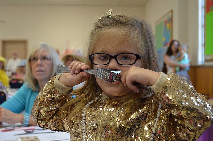 Emma Granthon makes a mustache using her fork and knife.