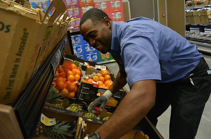 Employee Lee Tehart restocks pineapples.