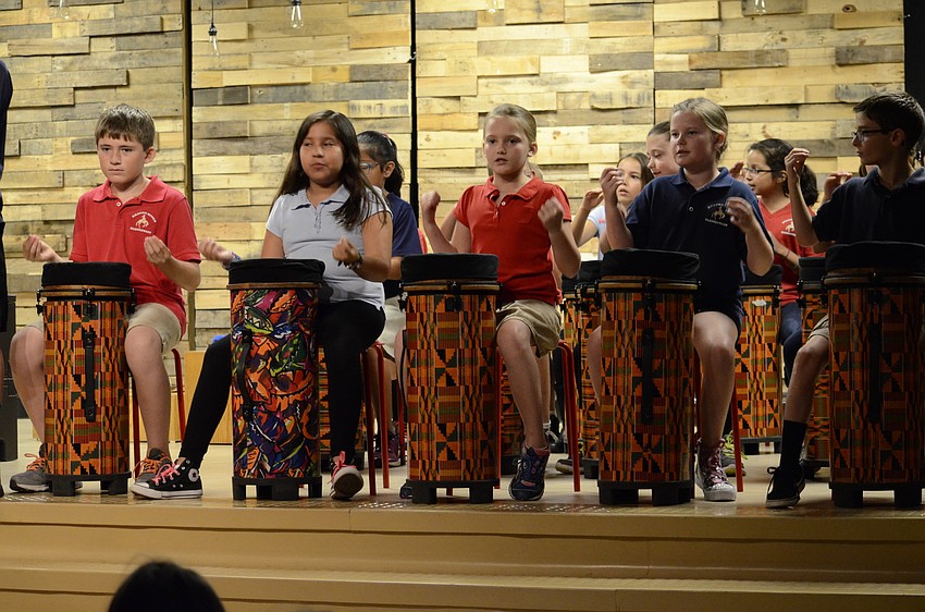 Third and fourth-graders beat the drum to the music.