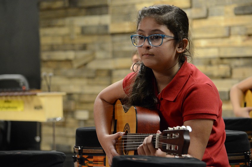 Kayla Foroughi strums the guitar.