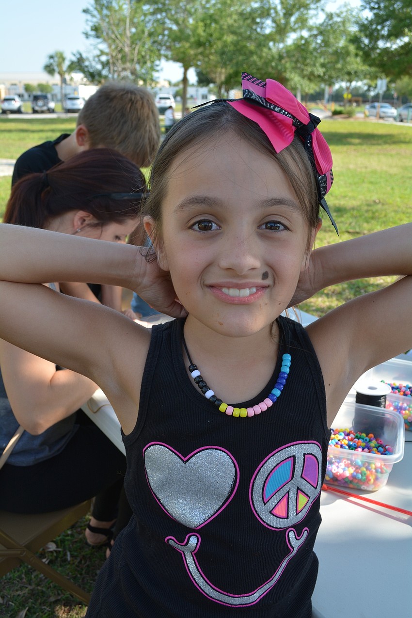 Izzy Harrell, 8, shows off the bead necklace she made from using binary code.