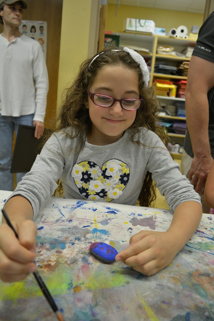 Nada Alhallaq, 8, paints a lady bug on a rock.