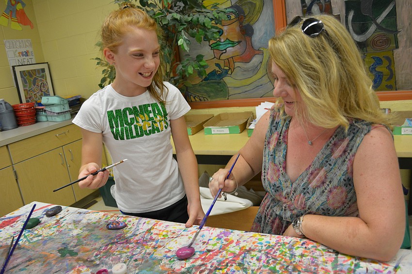 Abby Cummings, 10, paints a fish on a rock. Her mom, Posy, decides what to do next. 