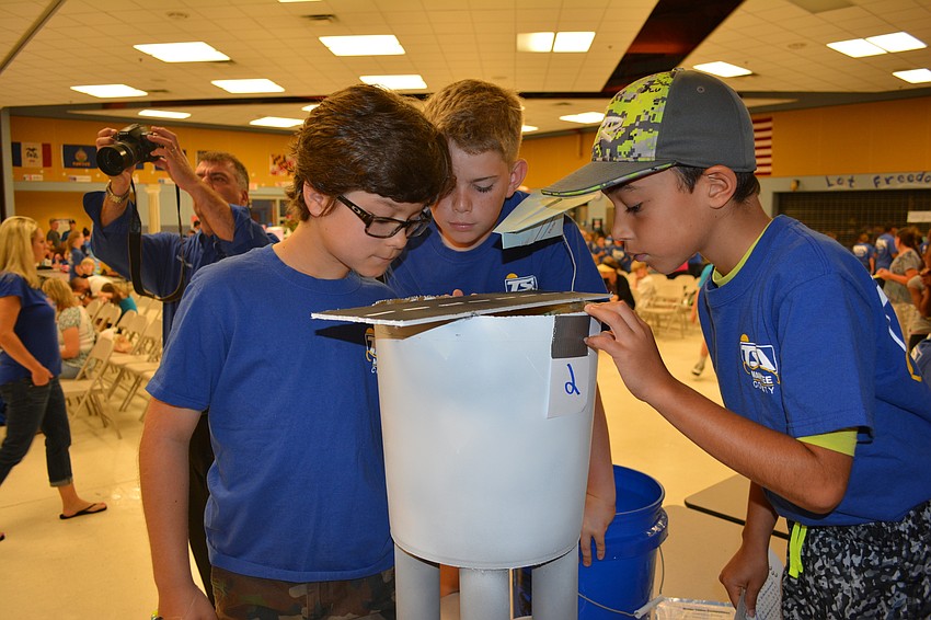 Ty Dauphas, Zachary Snyder and Mark Parsons of Freedom watch water drain from their creation during the timing challenge of the water tower competition.
