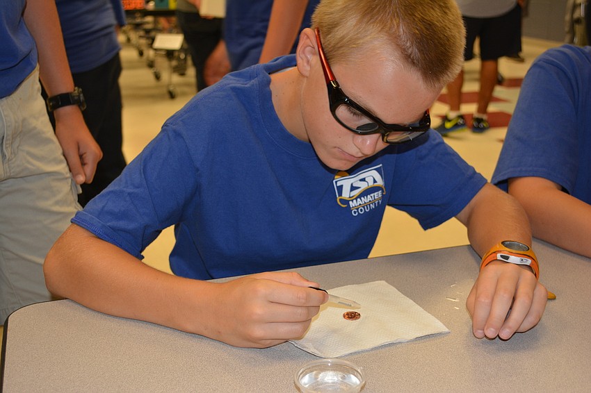 McNeal fifth grader Gabriel Hodge finds out how many drops of water will sit on top of a penny before it spills over.