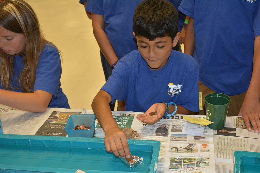 Luis Flores of Daughtrey Elementary loads up an aluminum boat with pennies.