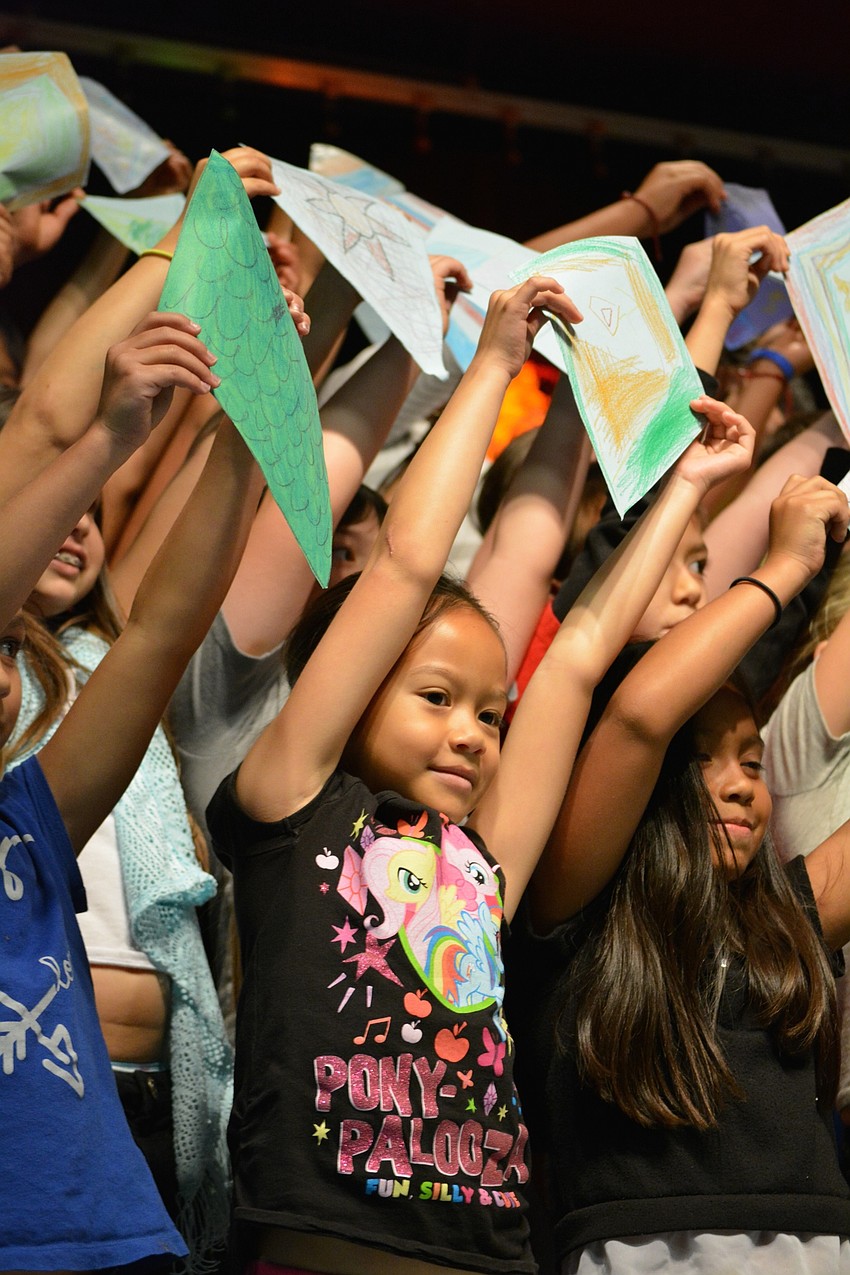 Ziarymar Cerdenio-Santiago, front center, waves a kite as she sings 