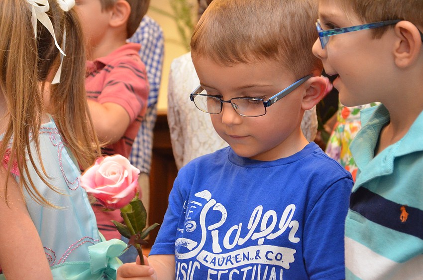 Cole Frazier examines his rose before giving it to First Presbyterian Preschool Director Clare Carter for her birthday.