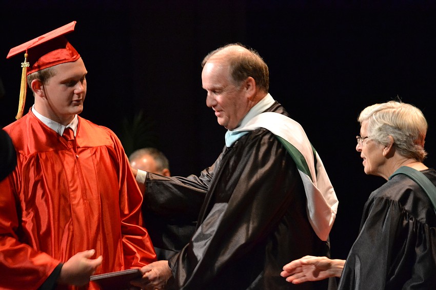 Nicholas Ackerson receives his diploma from Principal Steve Christie and greets Sister Lucia Haas.