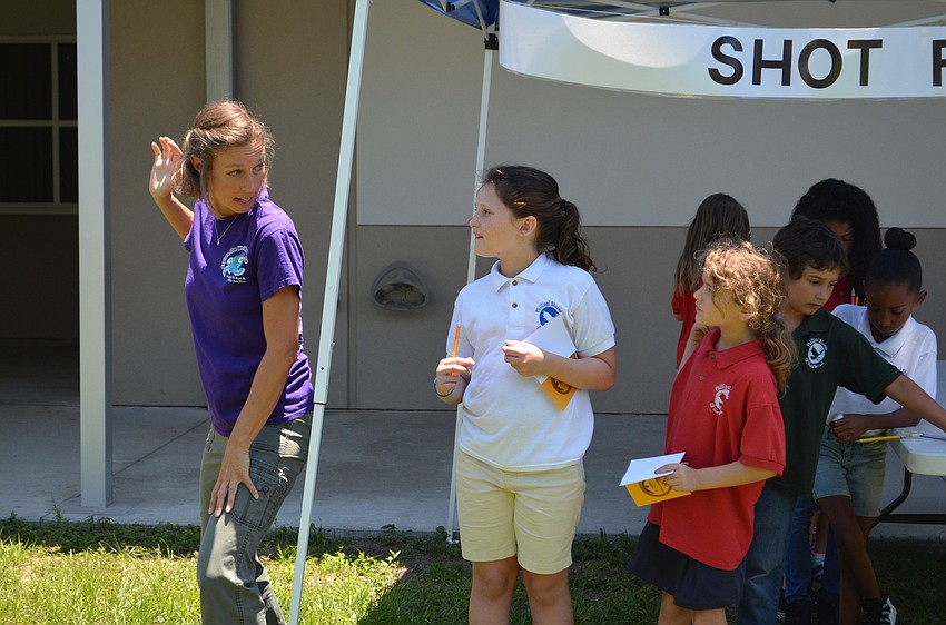 Colleen Halflants demonstrates how to launch the cotton balls for the cotton ball shot put event with Lola Anderson and Gabrielle Phillips.