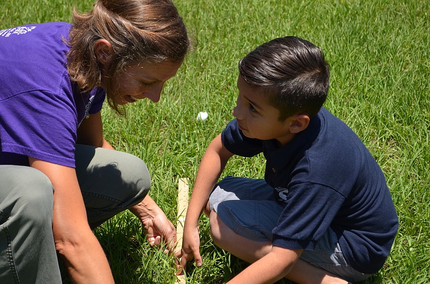 Colleen Halflants helps Jacob Rubio measure the distance he threw a cotton ball.