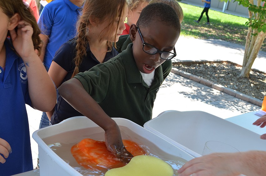 D'Andruss Flowers fills a sponge with water at the sponge squeeze event.