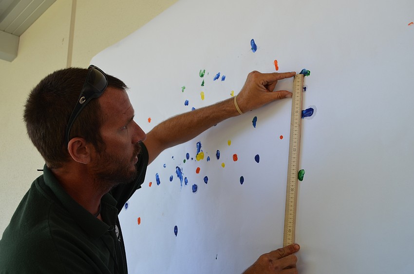 Phillippi Shores teacher James Anderson holds the ruler to measure the distance on the high jump event.