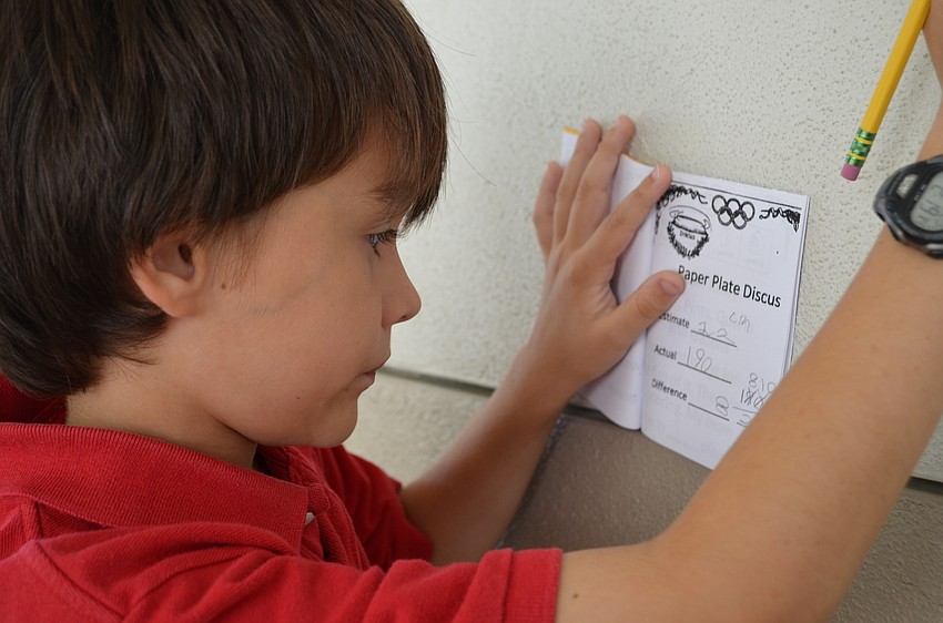 Nicolas McCurry calculates the difference between his estimate and actual distance for the paper plate discus event.