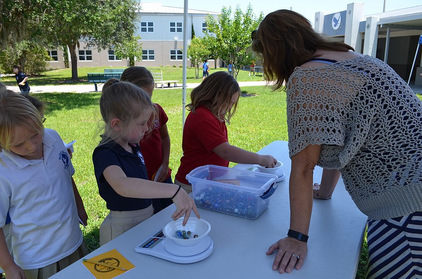 Pamela Doty explains the rules for the marble grab event where students weighed marbles to test their estimations.