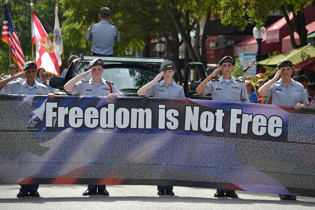 Sarasota Military Academy Cadets carry a banner with the 2015 parade theme â€œFreedom is not Free.â€