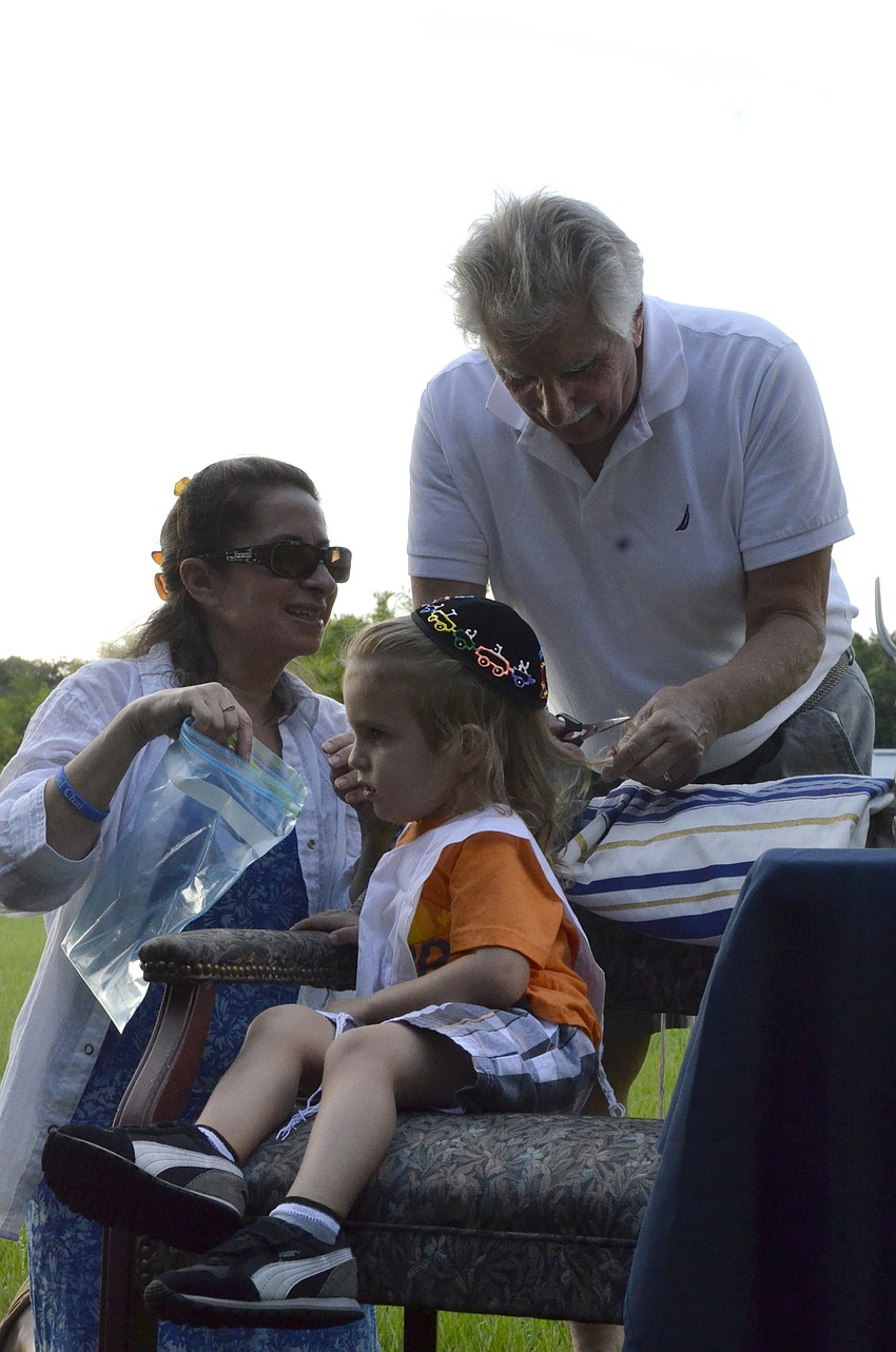 Three-year-old Gabriel Vallone gets his hair cut by his parents, Lauren Howitt-Vallone and Richard Vallone.