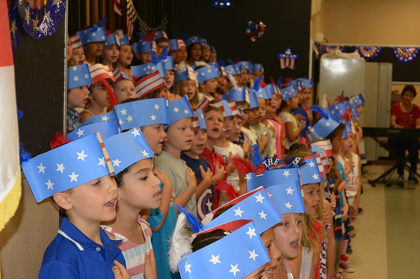 Witt students hold their hands over their hearts during a patriotic song.