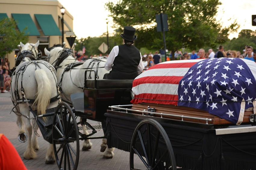 A horse-drawn carriage carried a casket covered by an American flag to end the parade.
