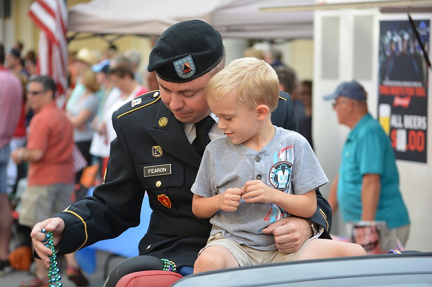 Robert Fearon of the National Guard and his son, Connor, ride in the parade and give out beads.