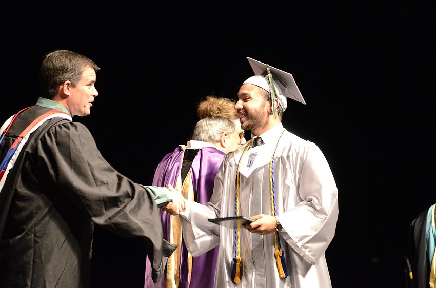 Dominic Rego shakes School Board Vice Chairman Charlie Kennedy's hand after getting his diploma.