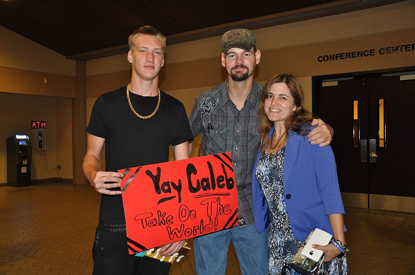 Adam Kersey holds up a sign for his brother, Caleb. Kevin Kalina and Joy Haugaard are close friends of the family and drove from Osteen, Fla., to watch Caleb graduate.