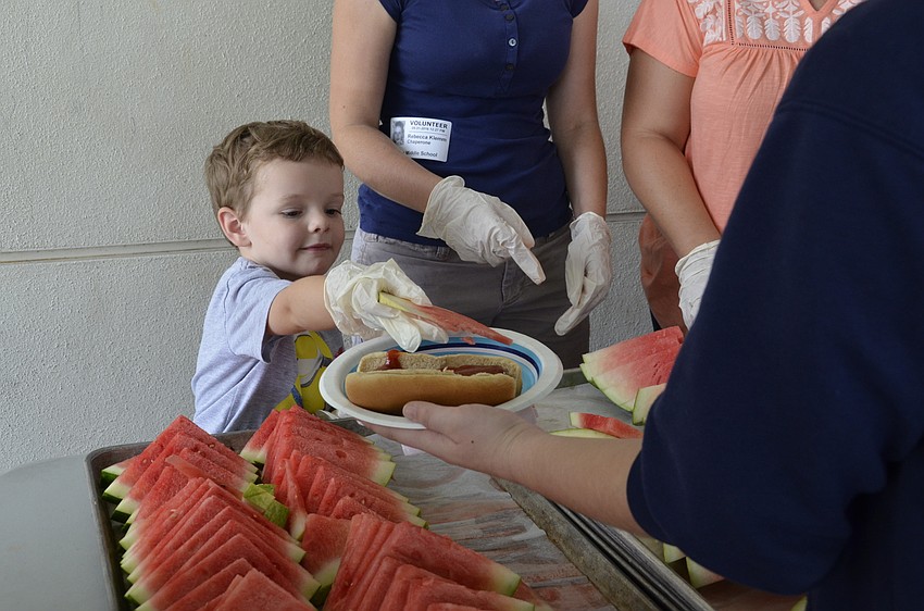 Ethan Klemm, 4, helps his mom, Rebecca, serve watermelon slices. Ethan has an older sister, Selena, in sixth grade.