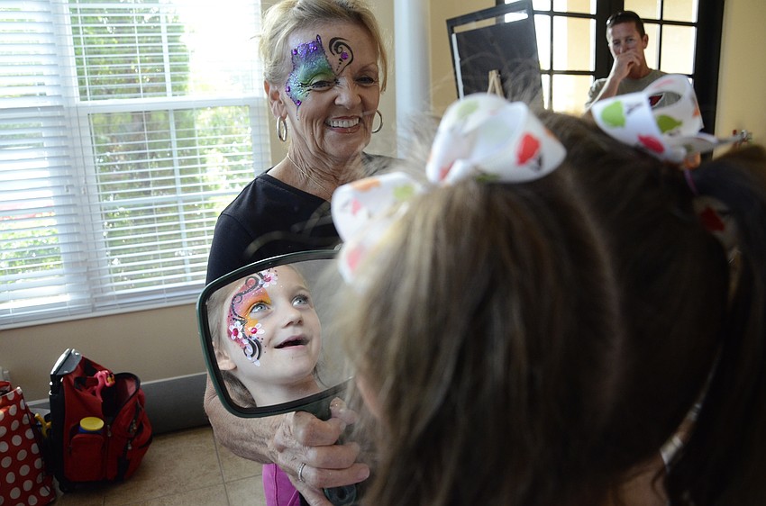 Harlow Griffith checks out her face after Judy Sherako put on the finishing touches.