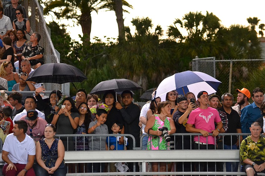 Parents and friends pop open umbrellas to shield themselves from the storm.