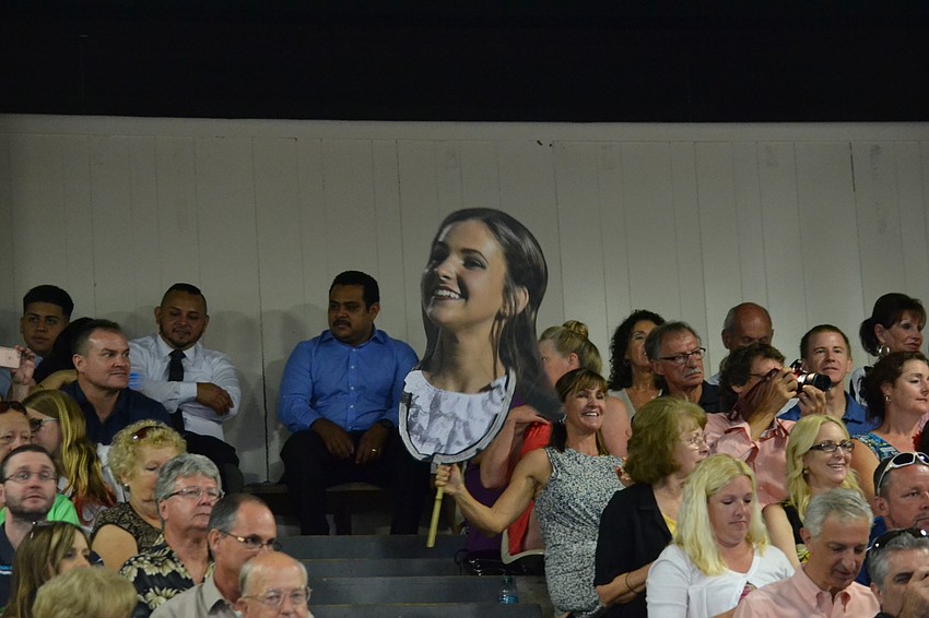 Betsy Pecor holds a cutout of her daughter Camber Pecor in the stands.